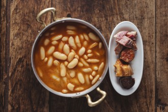 Fabada, a traditional asturian bean and pork stew, serving on a wooden table
