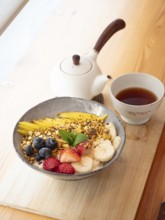 Oatmeal with granola, mango, banana, blueberries and strawberries served with tea
