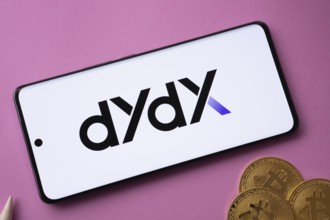 Dhaka, Bangladesh- 03 Oct 2025: Dydx logo on smartphone screen near Bitcoin coin and QR code on