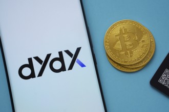 Dhaka, Bangladesh- 03 Oct 2025: Dydx logo on smartphone screen near Bitcoin coin and QR code on