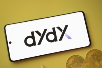 Dhaka, Bangladesh- 03 Oct 2025:Dydx logo on smartphone screen near Bitcoin coin and QR code on