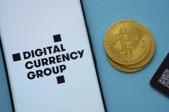 Dhaka, Bangladesh- 03 Oct 2025: Digital currency group logo on smartphone screen near Bitcoin coin