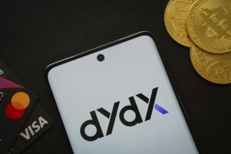 Dhaka, Bangladesh- 03 Oct 2025: Smartphone displaying Dydx logo surrounded by Bitcoin coins and