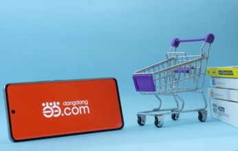 Dhaka, Bangladesh- 03 Oct 2025: Smartphone with Dangdang.com logo next to a small shopping cart and