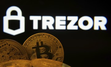 Dhaka, Bangladesh- 30 Sep 2025: Close-up of Bitcoin coins with the Trezor logo visible on a screen
