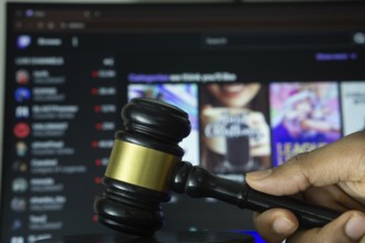 Dhaka, Bangladesh- 30 Sep 2025: A hand holds a gavel in front of a computer screen displaying