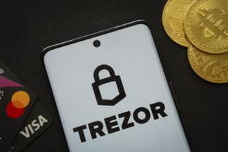Dhaka, Bangladesh- 30 Sep 2025: Smartphone displaying Trezor logo surrounded by Bitcoin coins and