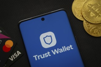 Dhaka, Bangladesh- 30 Sep 2025: Smartphone displaying Trust Wallet logo surrounded by Bitcoin coins