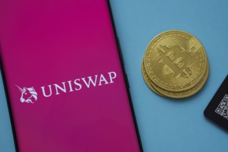 Dhaka, Bangladesh- 19 Sep 2025: Uniswap logo on smartphone screen near Bitcoin coin and QR code on