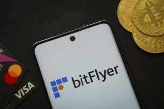 Dhaka, Bangladesh- 02 June 2025: Smartphone displaying Bitflyer logo surrounded by Bitcoin coins