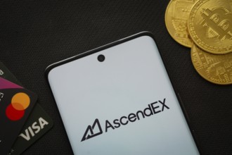 Dhaka, Bangladesh- 02 June 2025: Smartphone displaying AscendEX logo surrounded by Bitcoin coins