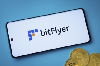 Dhaka, Bangladesh- 02 June 2025: Bitflyer logo on smartphone screen near Bitcoin coin and QR code