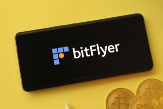 Dhaka, Bangladesh- 02 June 2025: Bitflyer logo on smartphone screen near Bitcoin coin and QR code
