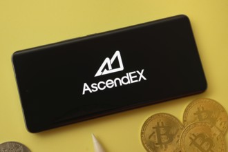 Dhaka, Bangladesh- 02 June 2025: AscendEX logo on smartphone screen near Bitcoin coin and QR code