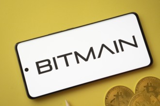 Dhaka, Bangladesh- 15 June 2025: Bitmain logo on smartphone screen near Bitcoin coin and QR code on