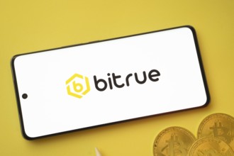 Dhaka, Bangladesh- 26 Aug 2025: Bitrue logo on smartphone screen near Bitcoin coin and QR code on