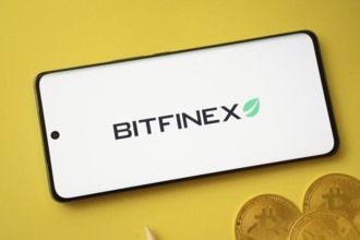 Dhaka, Bangladesh- 15 June 2025: Bitfinex logo on smartphone screen near Bitcoin coin and QR code