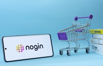 Dhaka, Bangladesh- 03 July 2025: Smartphone with nogin logo next to a small shopping cart and boxes