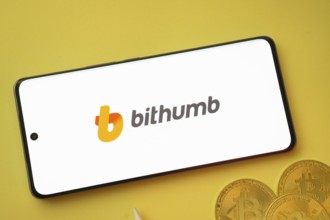 Dhaka, Bangladesh- 07 May 2025: Bithumb logo on smartphone screen near Bitcoin coin and QR code on
