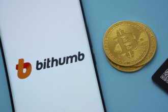 Dhaka, Bangladesh- 07 May 2025: Bithumb logo on smartphone screen near Bitcoin coin and QR code on