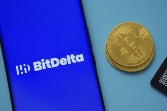 Dhaka, Bangladesh- 07 May 2025: BitDelta logo on smartphone screen near Bitcoin coin and QR code on