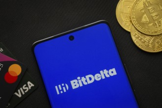 Dhaka, Bangladesh- 02 June 2025: Smartphone displaying BitDelta logo surrounded by Bitcoin coins