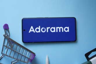 Dhaka, Bangladesh- 03 July 2025: Smartphone displaying Adorama logo with shopping cart on a blue