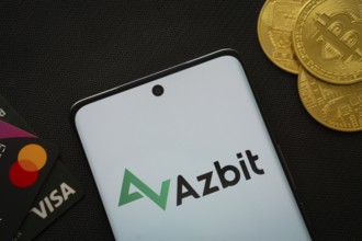 Dhaka, Bangladesh- 02 June 2025: Smartphone displaying Azbit logo surrounded by Bitcoin coins and