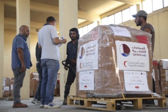 Relief workers unload boxes of medical aid provided by Qatar at Damascus International Airport,