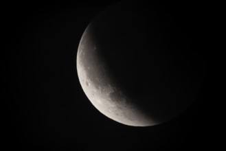 After a total lunar eclipse, the moon appears shortly after its rise in the evening sky as a