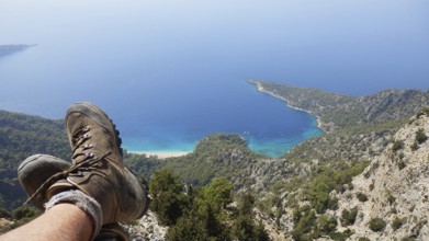 A person relaxes while hiking on a steep cliff in the mountains with spectacular views of hiking