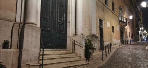 Cobblestone street in an old town at night, lined with historic buildings, Lisbon, Portugal