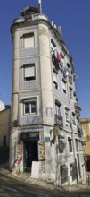 A tall, narrow building on a sloping street with typical facades, Lisbon, Portugal