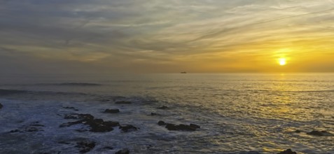 Colourful sunset over the calm sea with a ship on the horizon, hiking the Fisherman's Trail, Rota