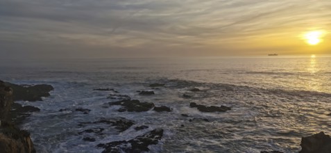 The picture shows a sunset over the sea with rocks in the foreground, hiking on the Fisherman's
