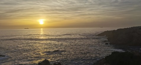 Calm sunset over the sea with two ships on the horizon, hiking the Fisherman's trail, Rota