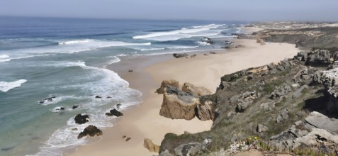 Rocky cliffs border an extensive sandy beach by the sea, hiking on the Fisherman's Trail, fishing