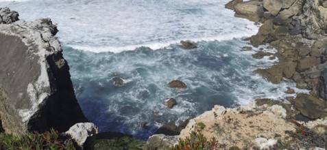 Turquoise waves crashing against rough cliffs by the sea, hiking the Fisherman's Trail, fishing