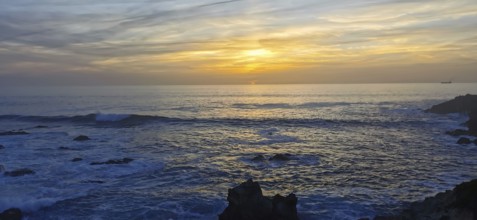 Sunset over a peaceful ocean with rocks in the foreground, hiking the Fisherman's trail, Rota