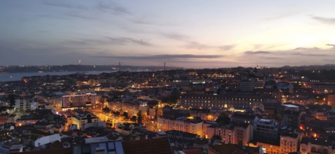 Panoramic view of Lisbon, city view with illuminated streets and buildings under a twilight sky,