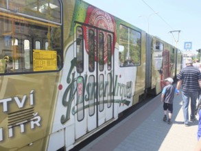 A tram with an advertising message from Pilsner Urquell passes a bus stop, Pilsen, Czech Republic