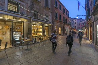 Photographers traveling in the old town of Venice, Veneto, Italy in the evening