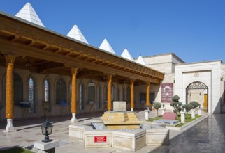 Traditional courtyard with fountain and decorated wooden pillars under clear skies, Istiklal Harbi