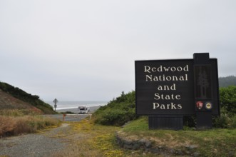 A sign at the entrance to Redwood National and State Park near a coastline, Redwood National Park,