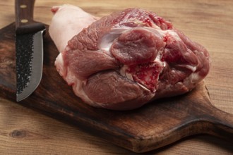 Raw pork knuckle, on a wooden chopping board, close-up, top view, no people