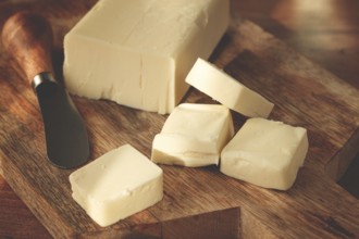 Butter briquette, on wrapping paper, wooden chopping board and butter knife, breakfast, rustic