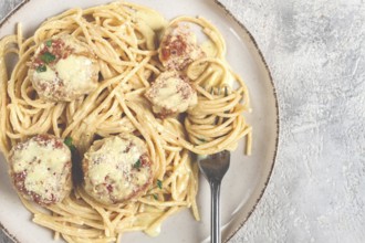 Spaghetti with chicken meatballs, with cream sauce, and parmesan cheese, and decorated with