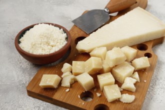 Freshly sliced and grated cheese, parmesan cheese, Gran gusto. Grana padano. on a wooden chopping