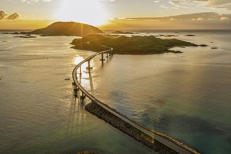 Sommaroy Bridge connecting Kvaloya Island to Sommaroy Island, warm light at sunset, aerial view,