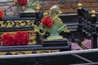Mythological horse figures and red pompoms decorate the gondola, Venice, Veneto, Italy